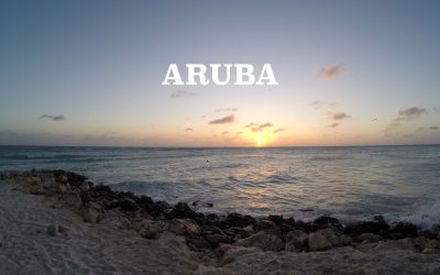 A beach in Aruba with the sun setting and the word "Aruba" printed on top