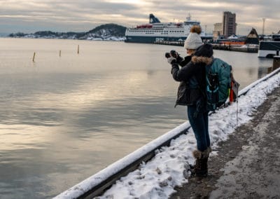 Alice Ford in Oslo with her Shimoda X30 backpack taking a photo beside the water