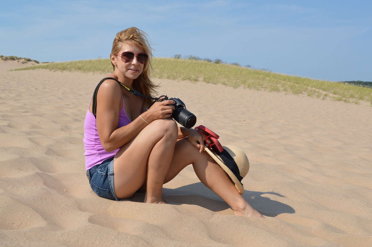 Alice Ford sitting in the sand holding a camera