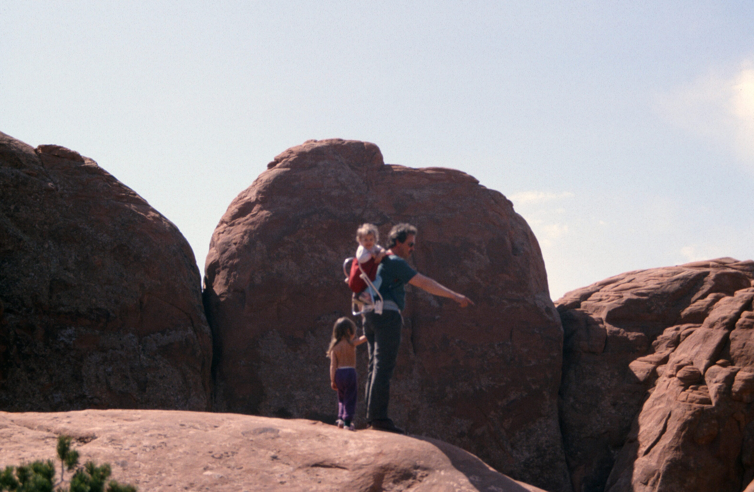 Man with two girls in a backpack in Arches national Park Utah 