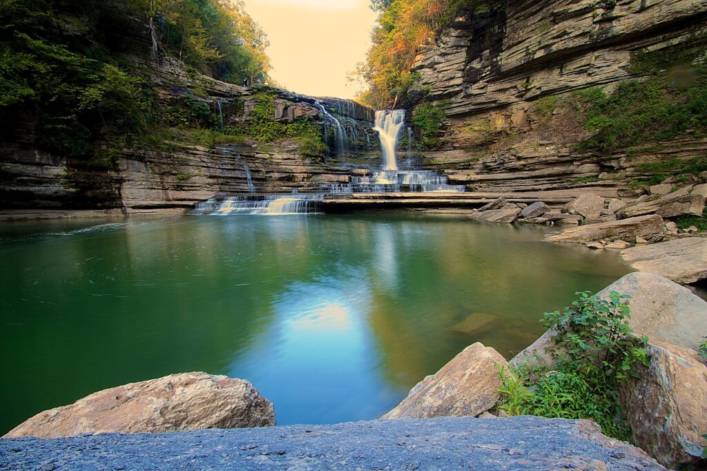 The empty swimming hole at Cummins Falls in Cookeville, Tennessee seen at sunset with boulders in the foreground and inviting water