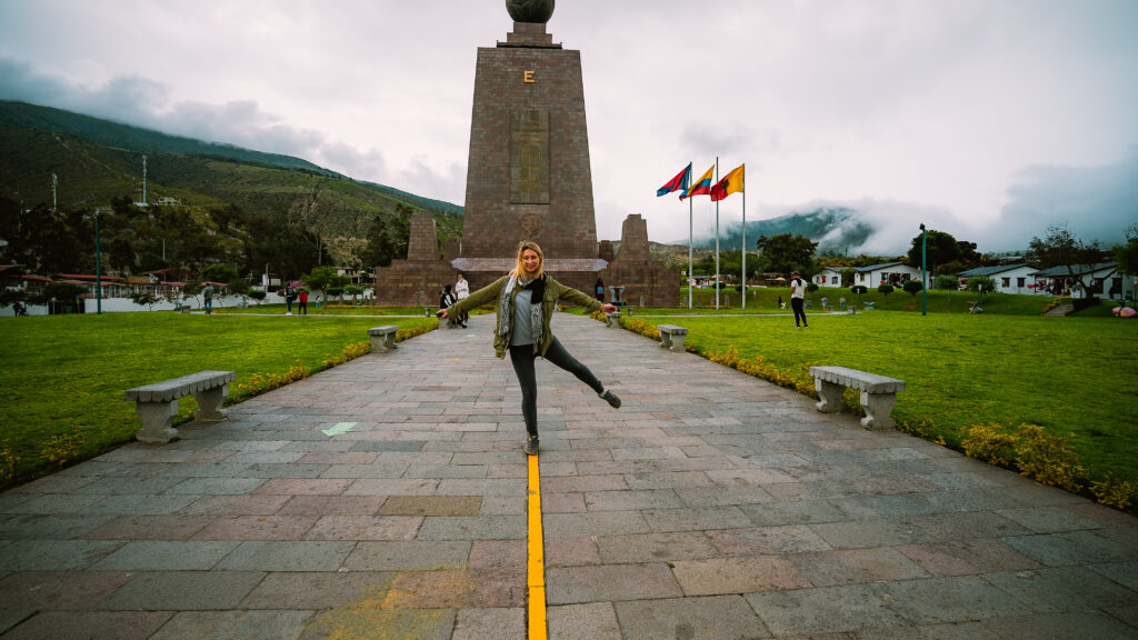 woman stands on the equatorial line at the center of the world outside Quito Ecuador