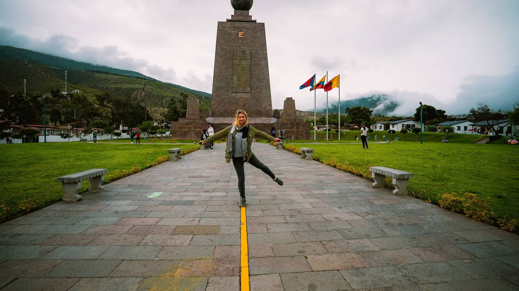 woman stands on the equatorial line at the center of the world outside Quito Ecuador 