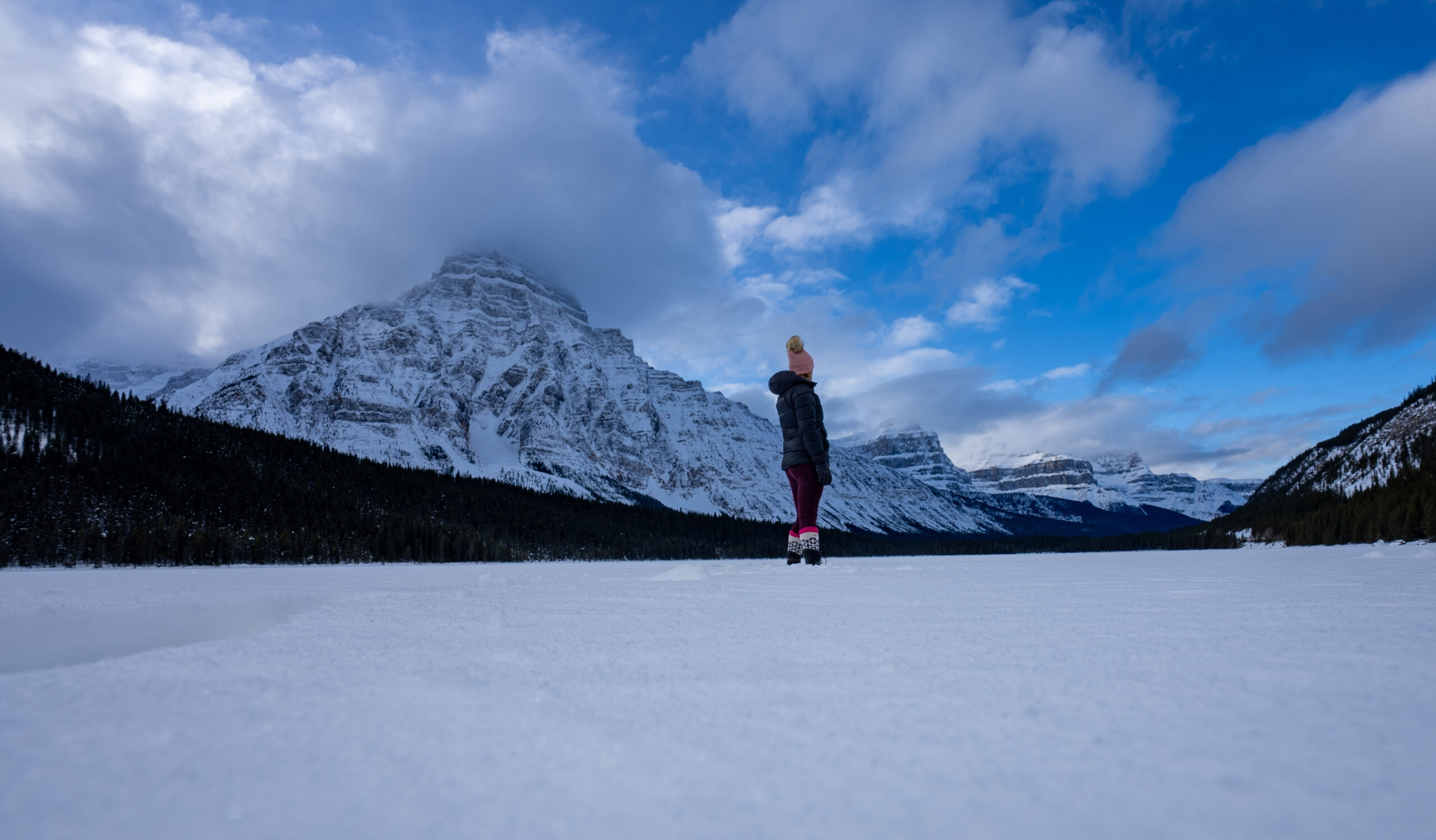 Woman standing on a frozen lake along the icefields parkway in Banff National Park 