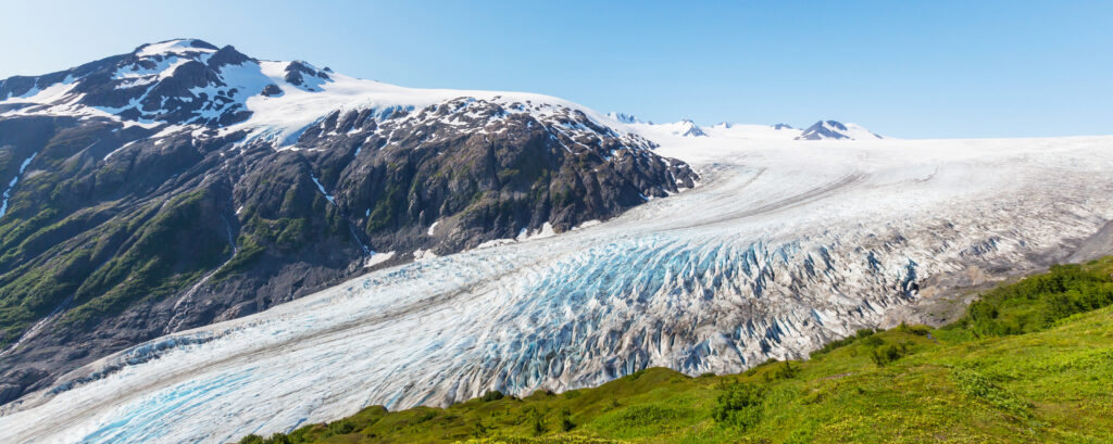 View of Exit Glacier with green grass in the foreground at famous Alaska national park, Kenai Fjords National Park on a 10-day road trip route