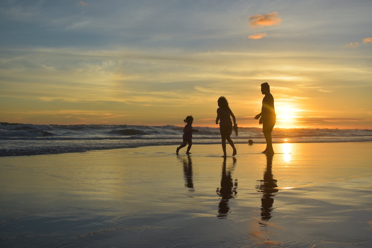 A family plays together on the beach during sunset