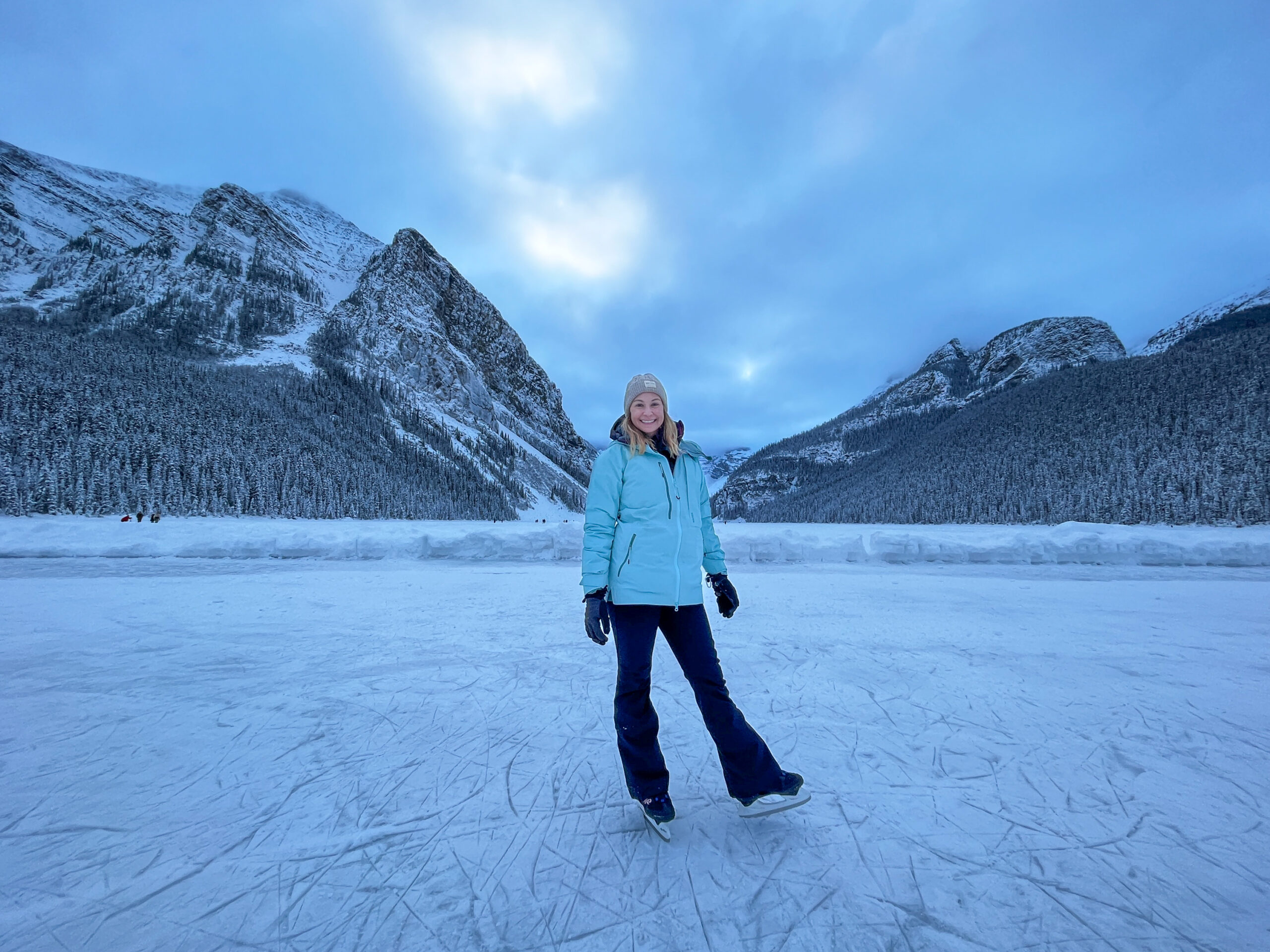 Woman on ice skates standing on Lake Louise in winter