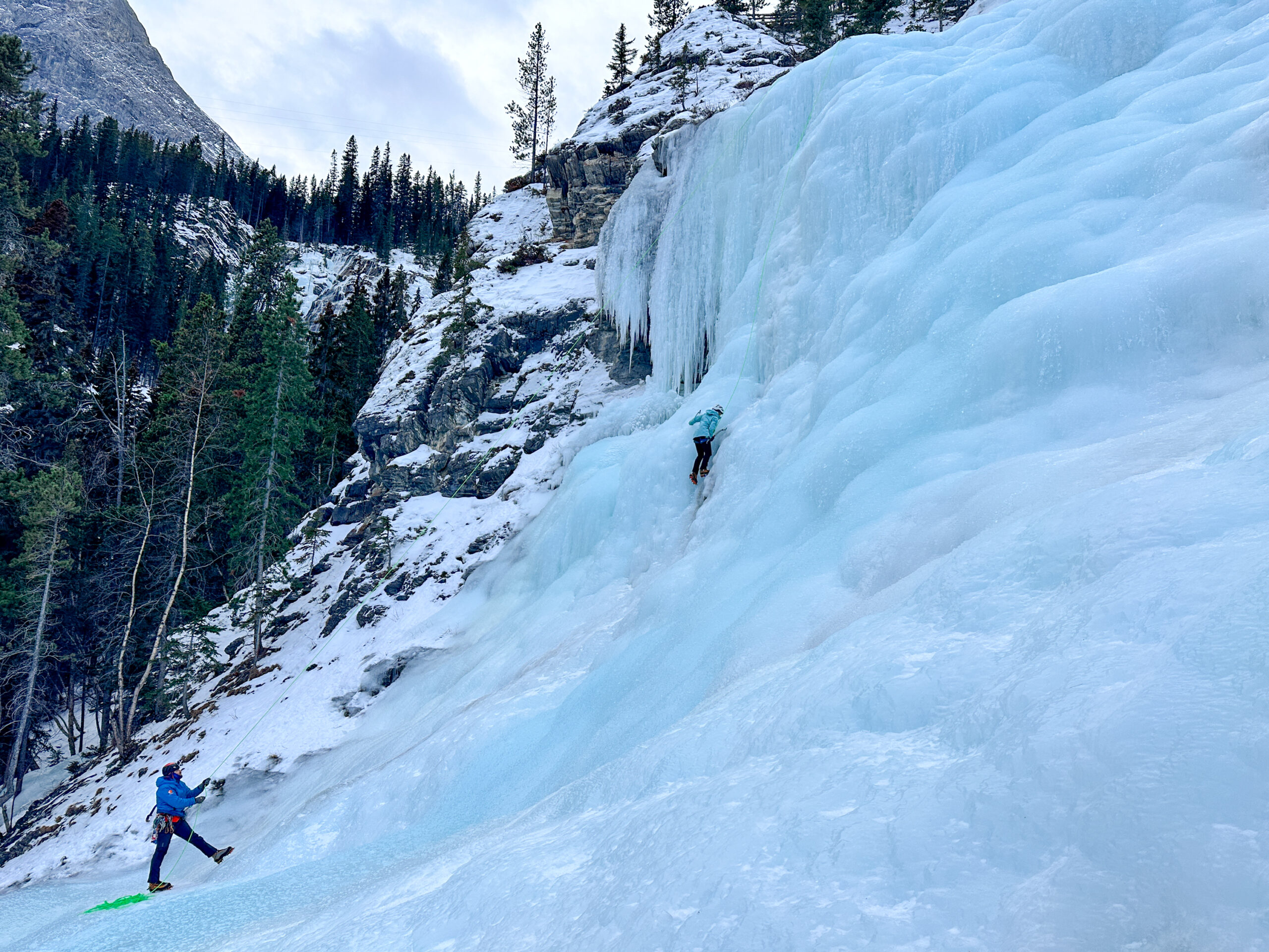 Woman ice climbing a frozen waterfall