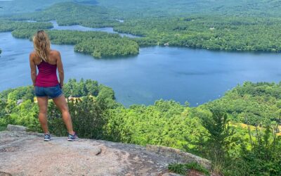 Woman stands on edge of rocky outcropping in New Hampshires WHite MOuntains