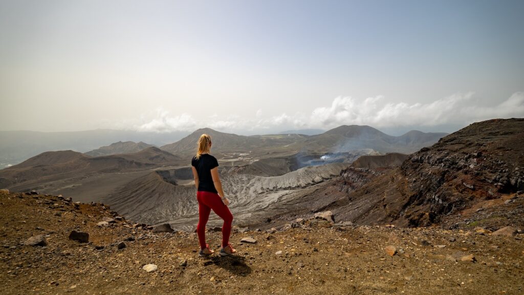 Alice Ford standing at the top of the summit loop on Mt. Aso, one of the top adventure destinations in Japan