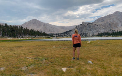 A woman stands looking towards Cottonwood Lake surrounded by mountains in California