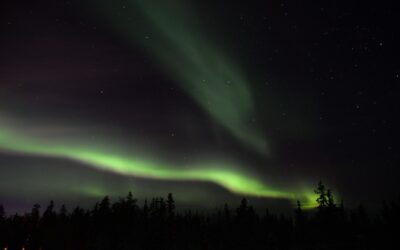 A streak of green northern lights dance through the night sky