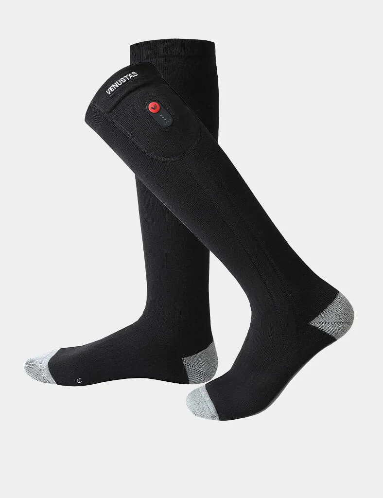 Pictured are a black pair of Venustas Heated Socks, shown with the button that activates the heat for a holiday gift guide featuring the best gifts for outdoor lovers