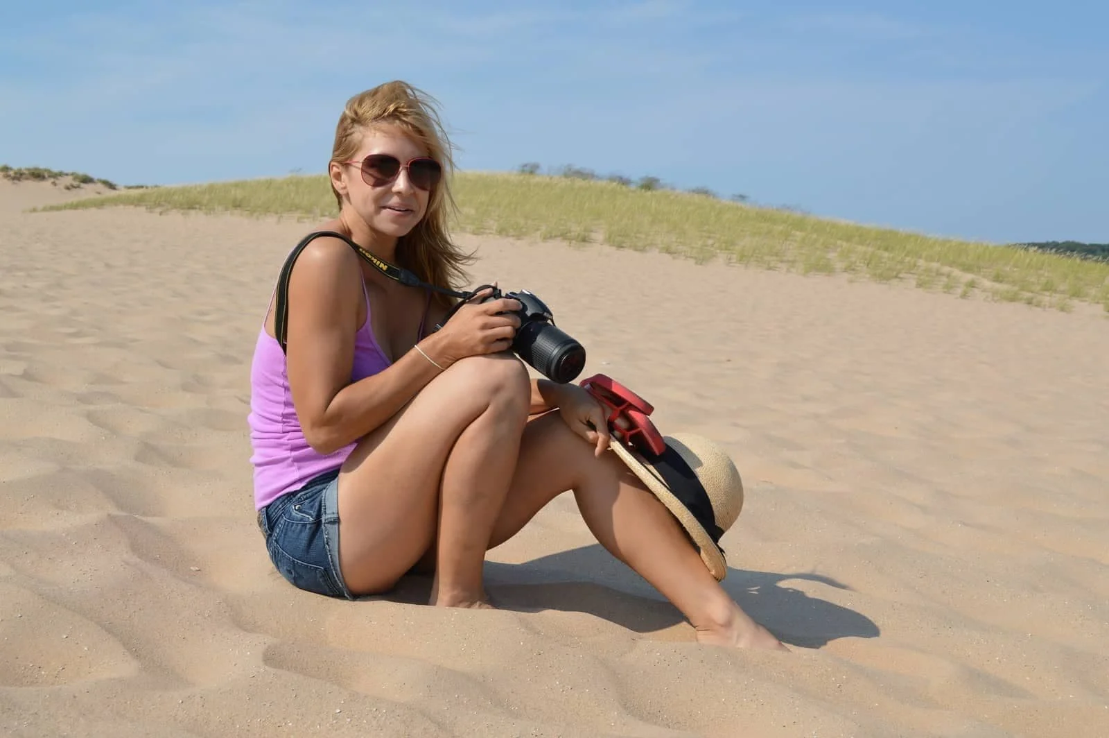 Alice sitting in the sand dunes with a camera
