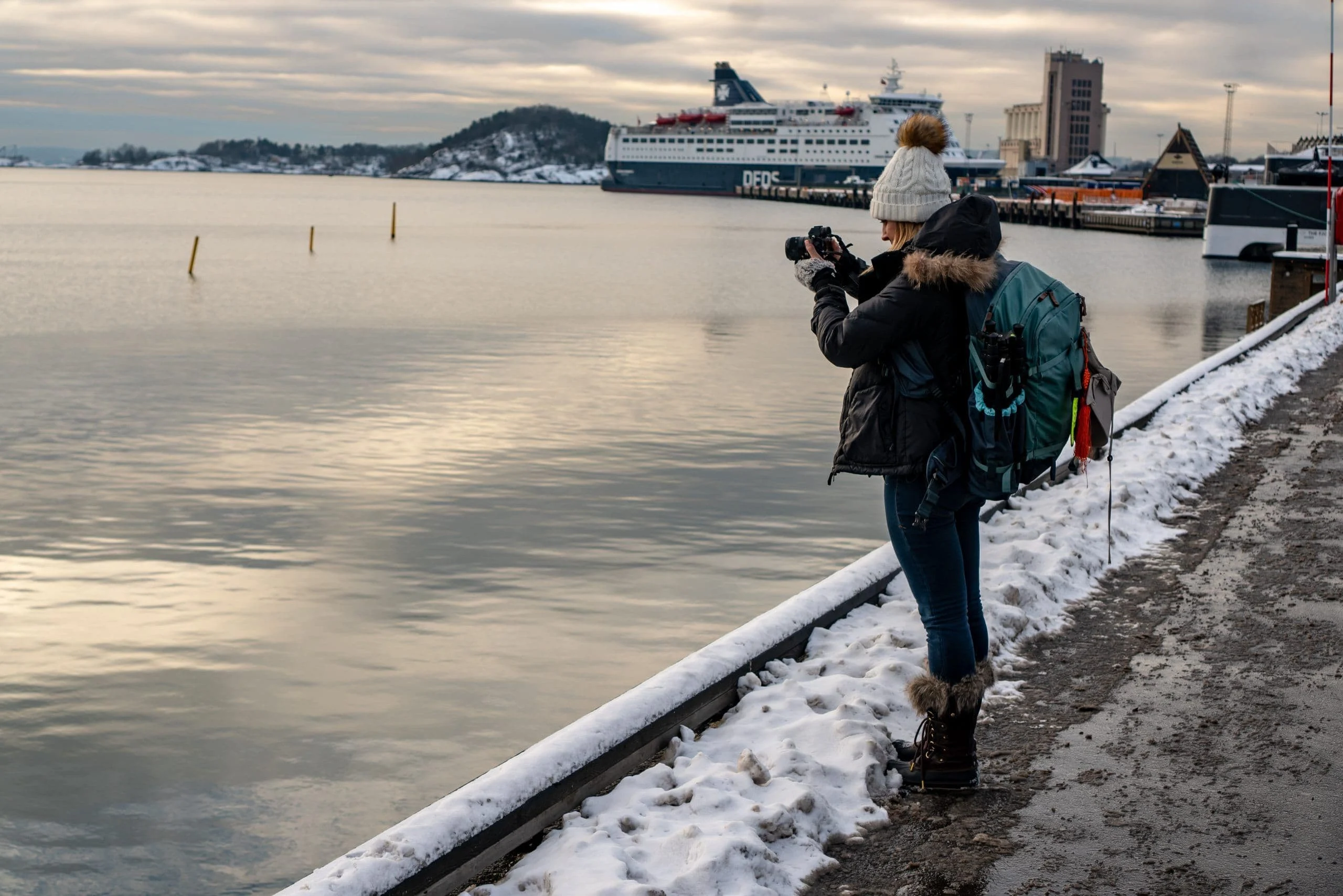 Alice filming with a camera on a winter harbour wall
