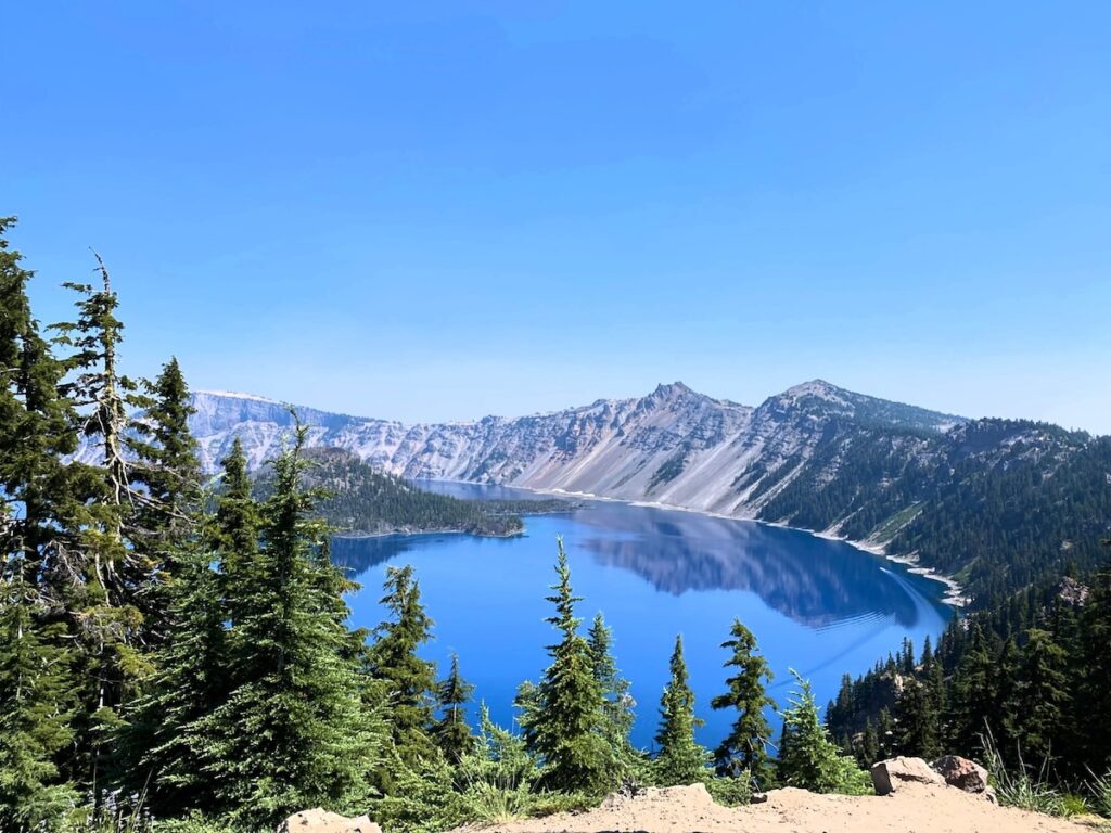 Aerial view of tree-surrounded Crater Lake in Crater Lake National Park, an outstanding Pacific Northwest national park with hiking trails and boat tours