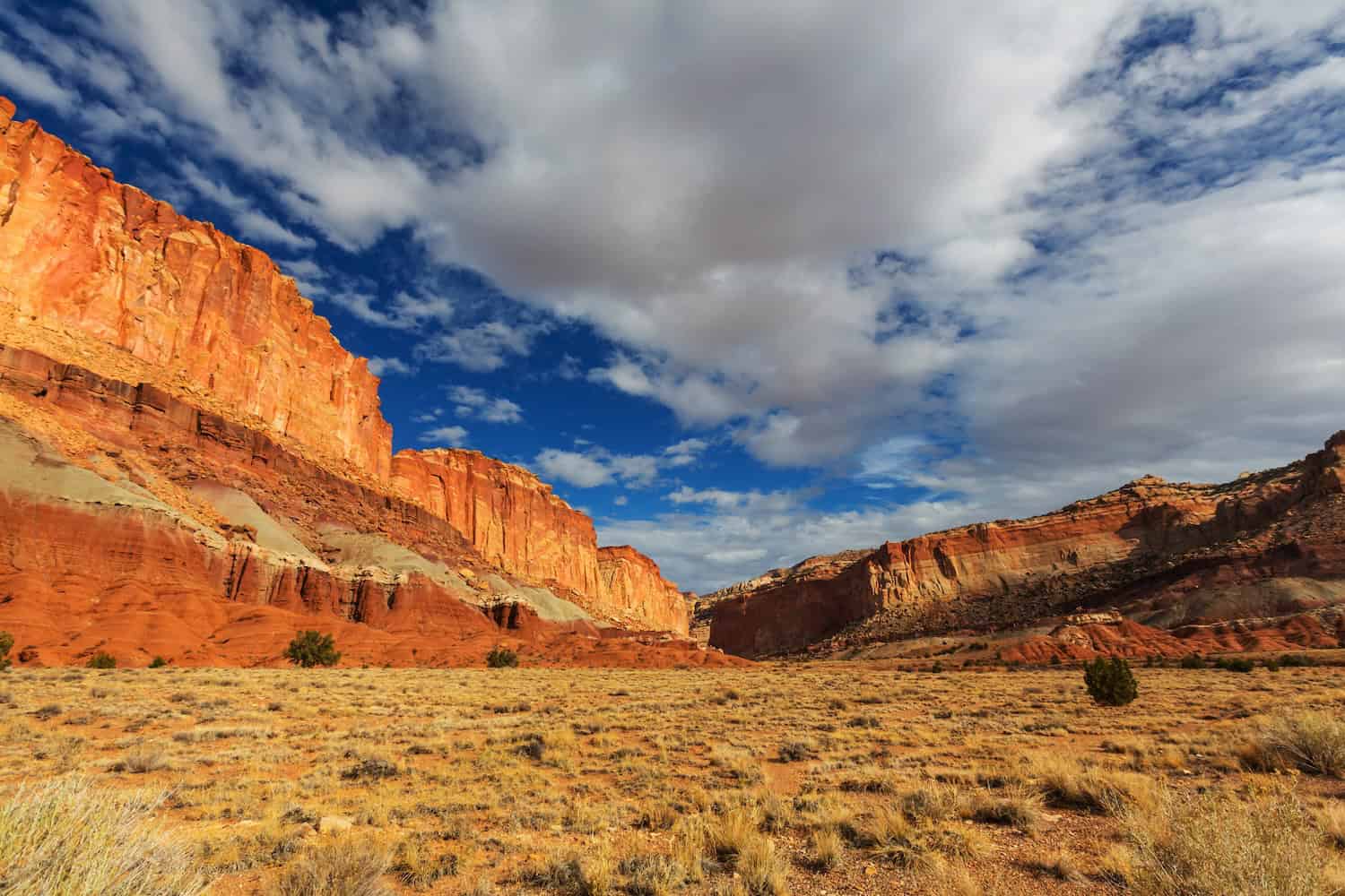 Red rock formations shown for a Capitol Reef National Park guide, set against blue skies and fluffy clouds for contrast