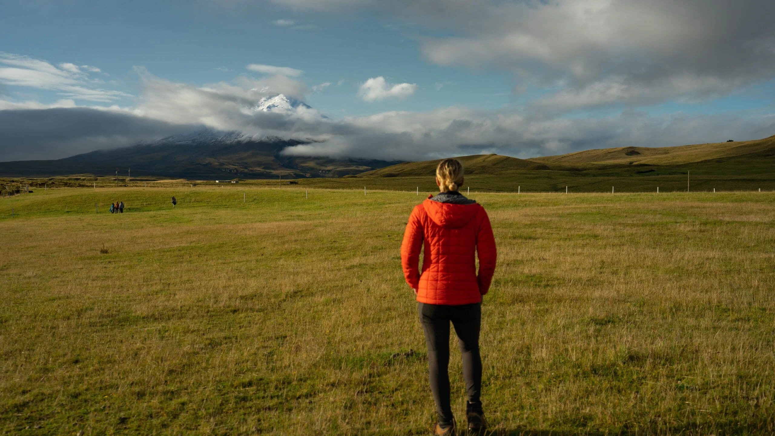 A hiker in a red jacket on the high páramo below Cotopaxi volcano