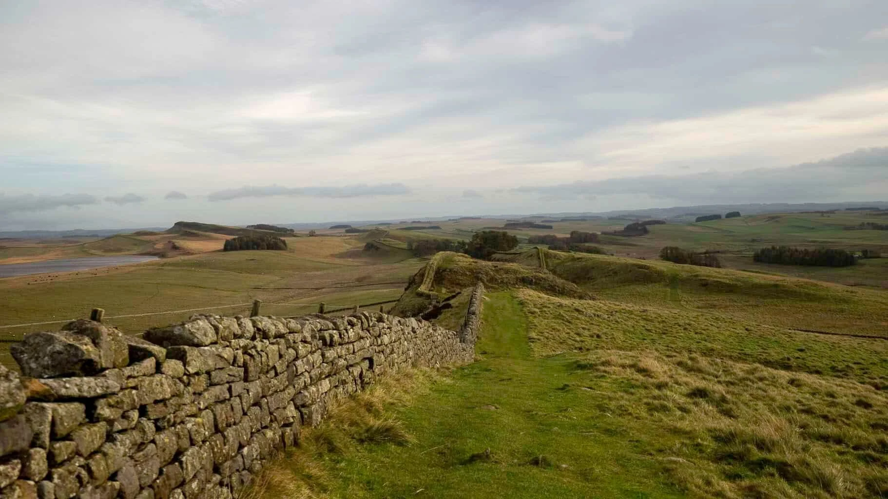 Hadrian’s Wall running across green moorland under a grey sky