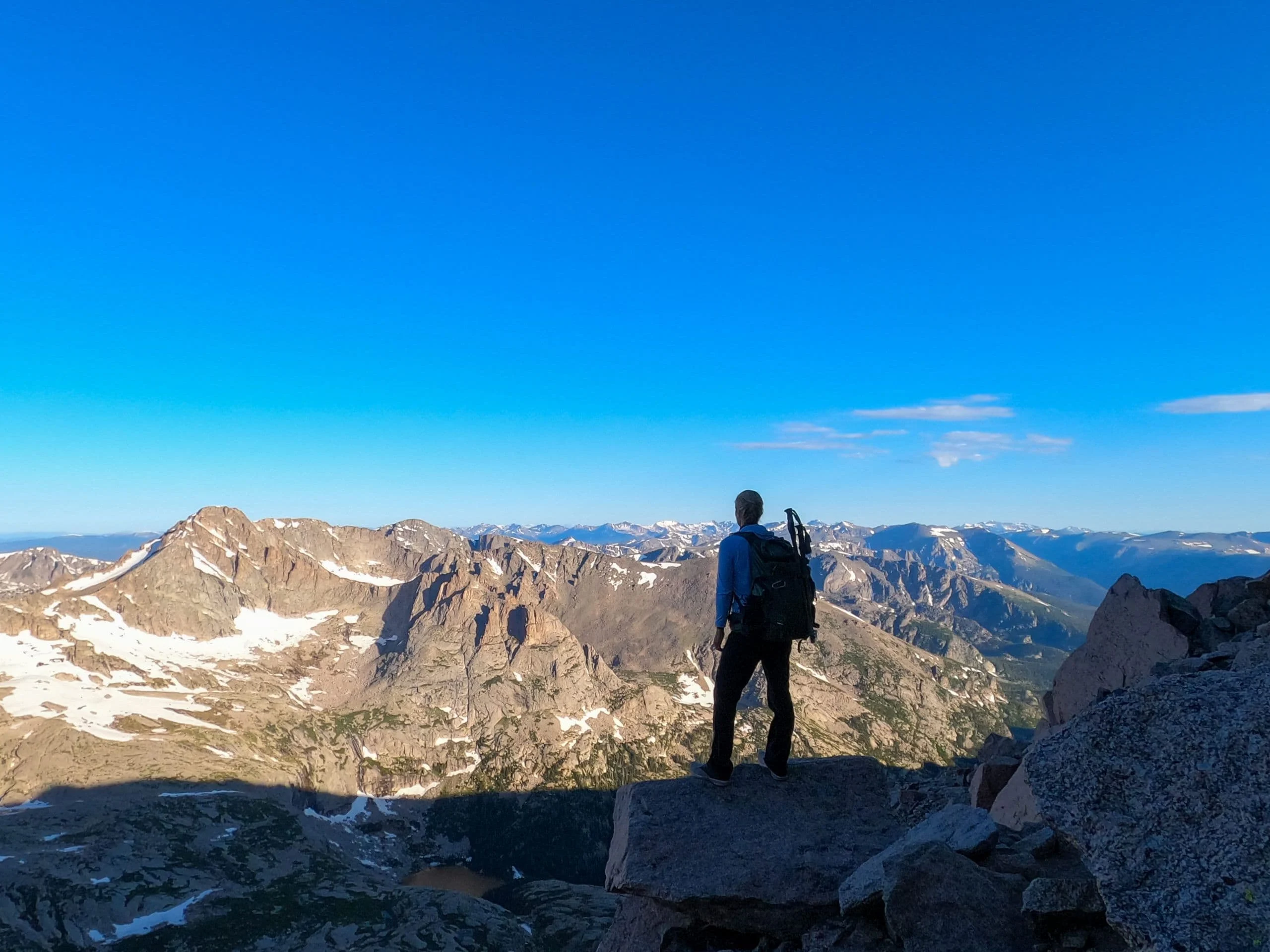 Alice looking out over Colorado peaks from a rocky summit ridge