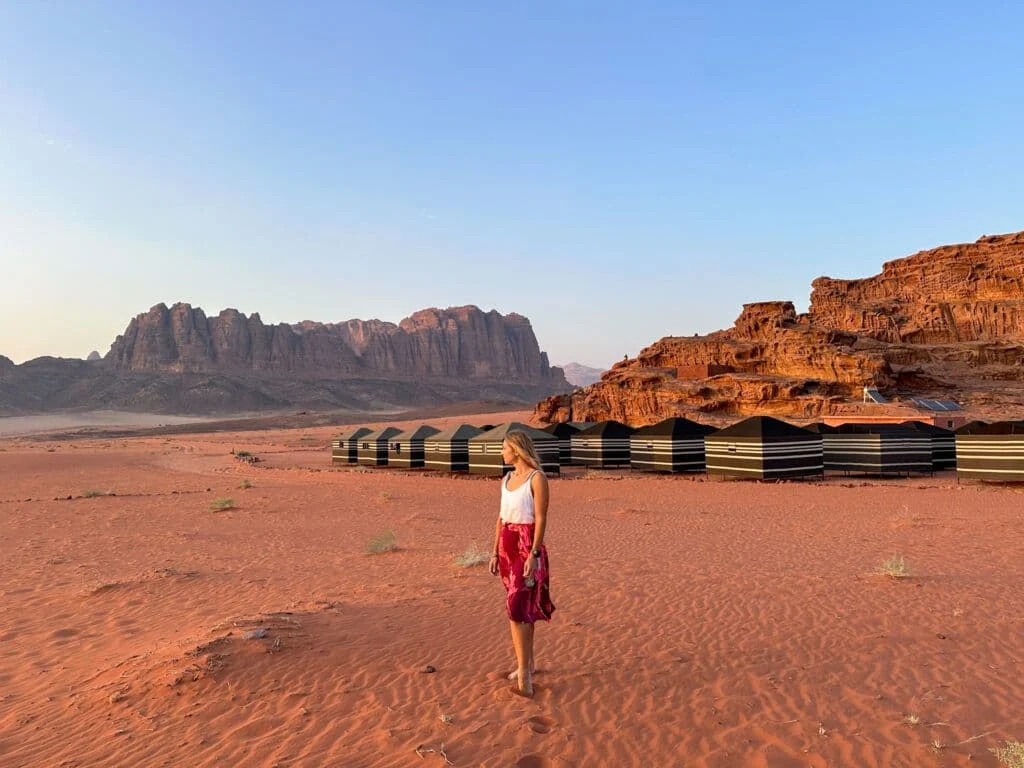 Alice walking across red sand toward the cliffs of Wadi Rum, Jordan