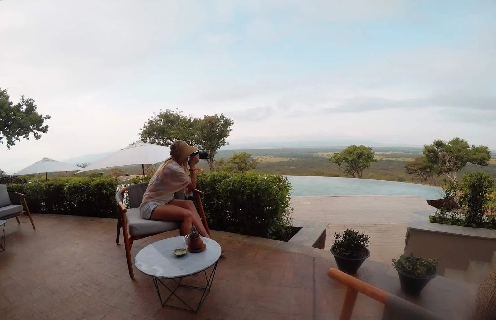 Alice on a lodge terrace with binoculars, looking across the Serengeti